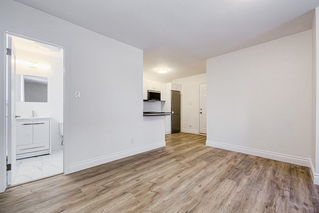 a living room and kitchen with white walls and wood flooring at 608 Church Apartments, Toronto, ON