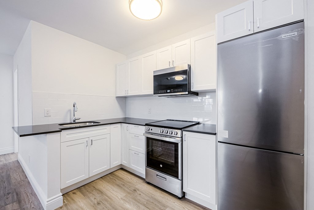 a renovated kitchen with white cabinets and stainless steel appliances at 608 Church Apartments, Toronto