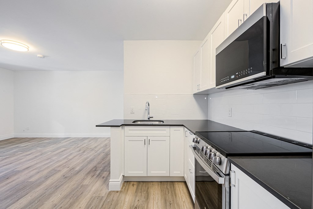 A kitchen with black countertops and white cabinets. at 608 Church Apartments, Ontario
