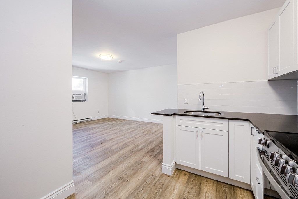 an empty kitchen and living room with white cabinets and wood floors at 608 Church Apartments, Toronto, Ontario