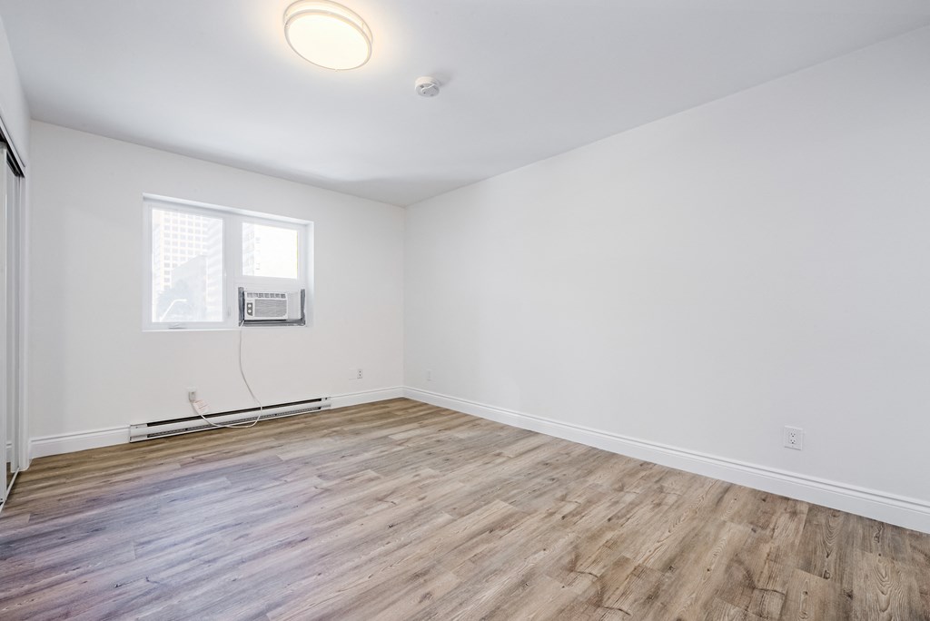 an empty living room with white walls and wood flooring at 608 Church Apartments, Toronto, M4Y 2E7