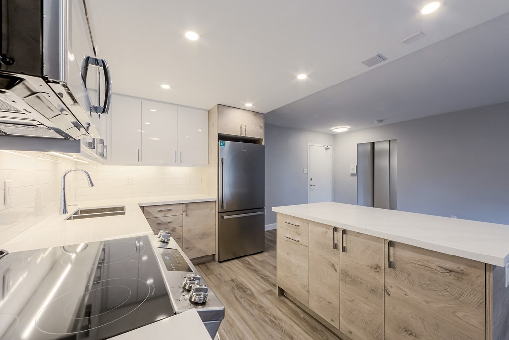 a large kitchen with white counter tops and stainless steel appliances at 70 Park, Mississauga