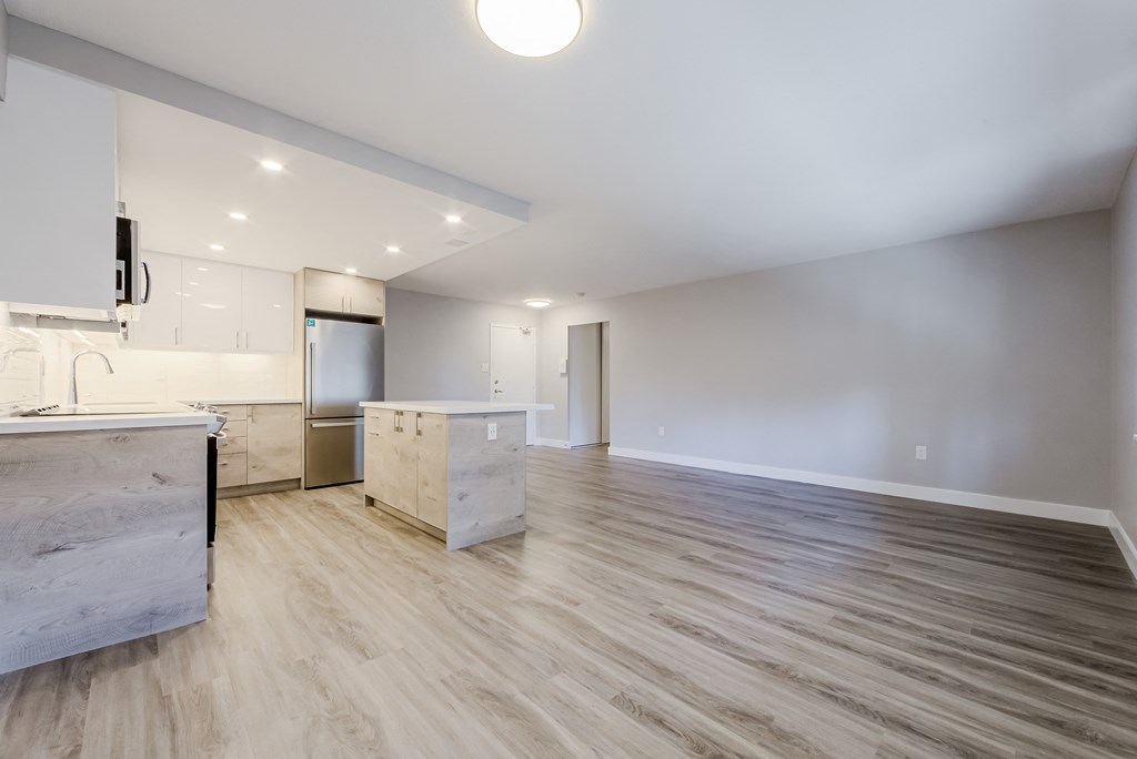 an empty kitchen and living room with white walls and wood flooring at 70 Park, Canada
