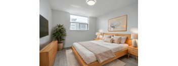 A bedroom with a large bed, a wooden nightstand, and a potted plant. at 70 Park, Mississauga, Canada