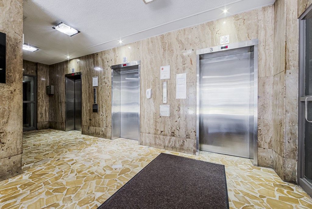 a lobby with elevators and a yellow rug on the floor at 70 Park, Mississauga