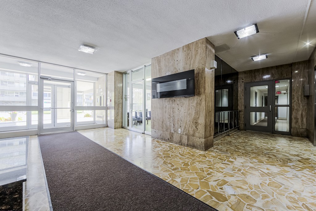 a lobby with a tv on the wall and glass doors at 70 Park, Canada, L5G 1M5