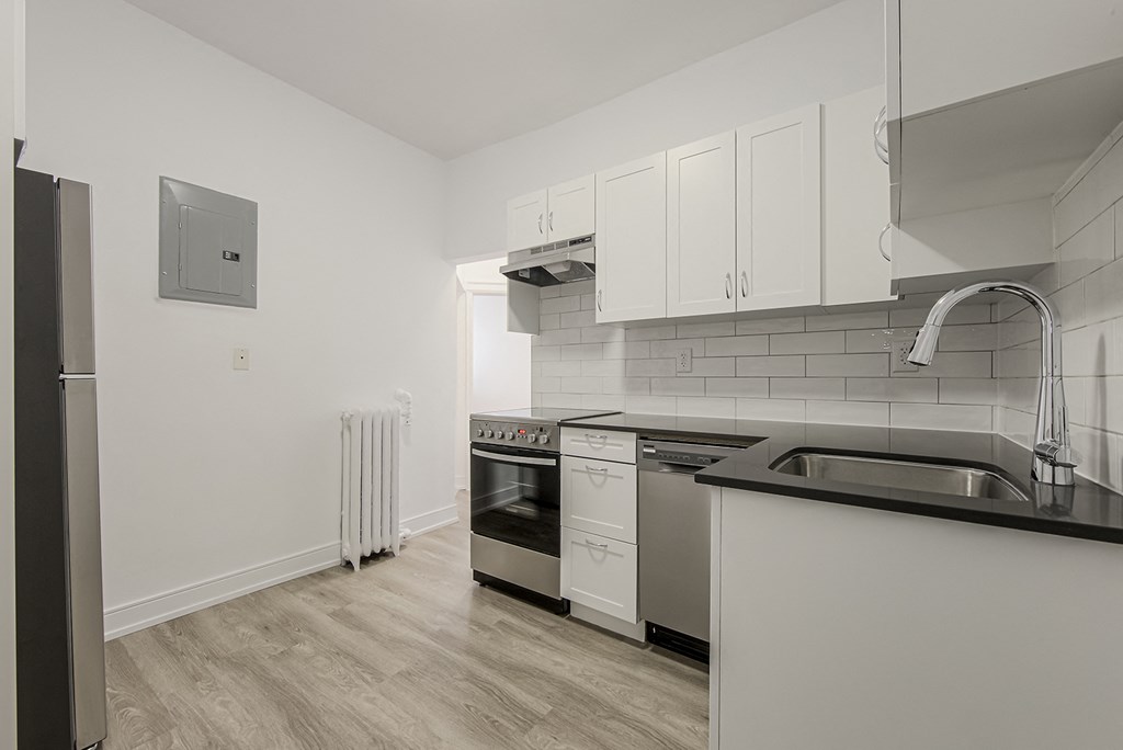 an empty kitchen with white cabinets and stainless steel appliances at 723 Bloor Apartments, Canada, M6G 1L5
