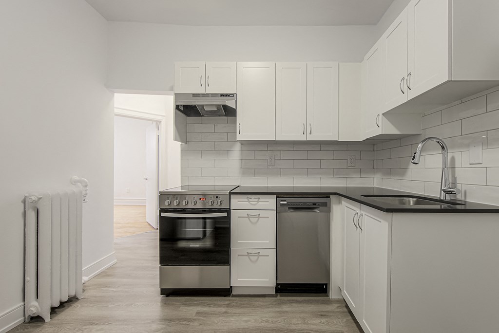 A kitchen with white cabinets and a black countertop at 723 Bloor Apartments, Toronto, M6G 1L5