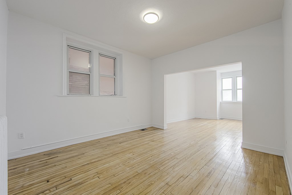 an empty living room with white walls and wooden floors at 723 Bloor Apartments, Toronto, CA, M6G 1L5