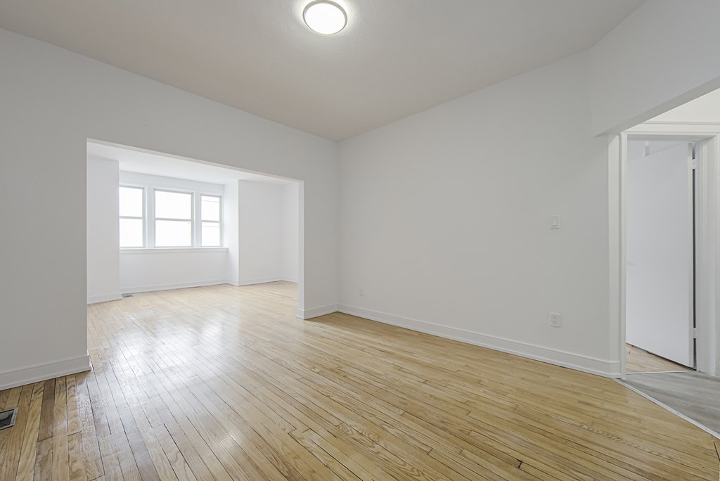 an empty living room with white walls and wood floor at 723 Bloor Apartments, Canada