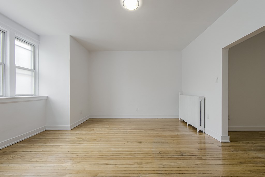 A room with wooden floors and a white radiator at 723 Bloor Apartments, Canada, M6G 1L5