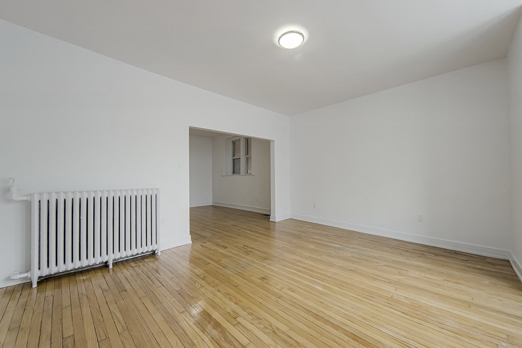 the living room and dining room of a house with wood flooring and a radiator at 723 Bloor Apartments, Canada, M6G 1L5