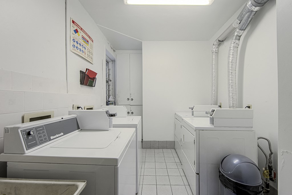 A clean white bathroom with a toilet, sink, and a washing machine at 723 Bloor Apartments, Toronto, M6G 1L5