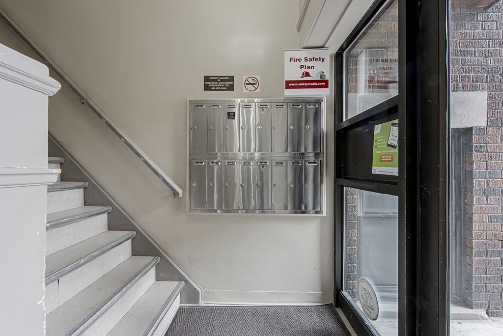 an empty stairwell with a door to a building with mailboxes on the stairs at 723 Bloor Apartments, Toronto, CA