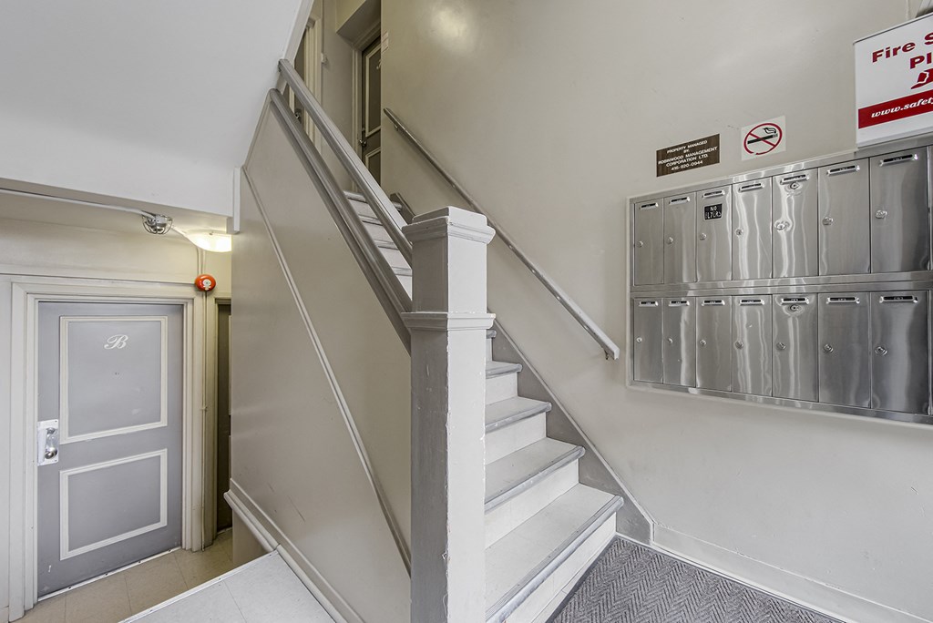 the stairway up to the second floor of a building with lockers and stairs at 723 Bloor Apartments, Toronto, CA, M6G 1L5