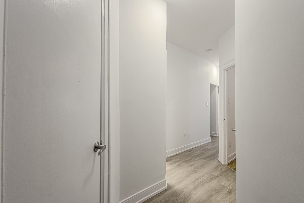 a bedroom with white walls and wood flooring and a door to a hallway at 723 Bloor Apartments, Toronto, CA