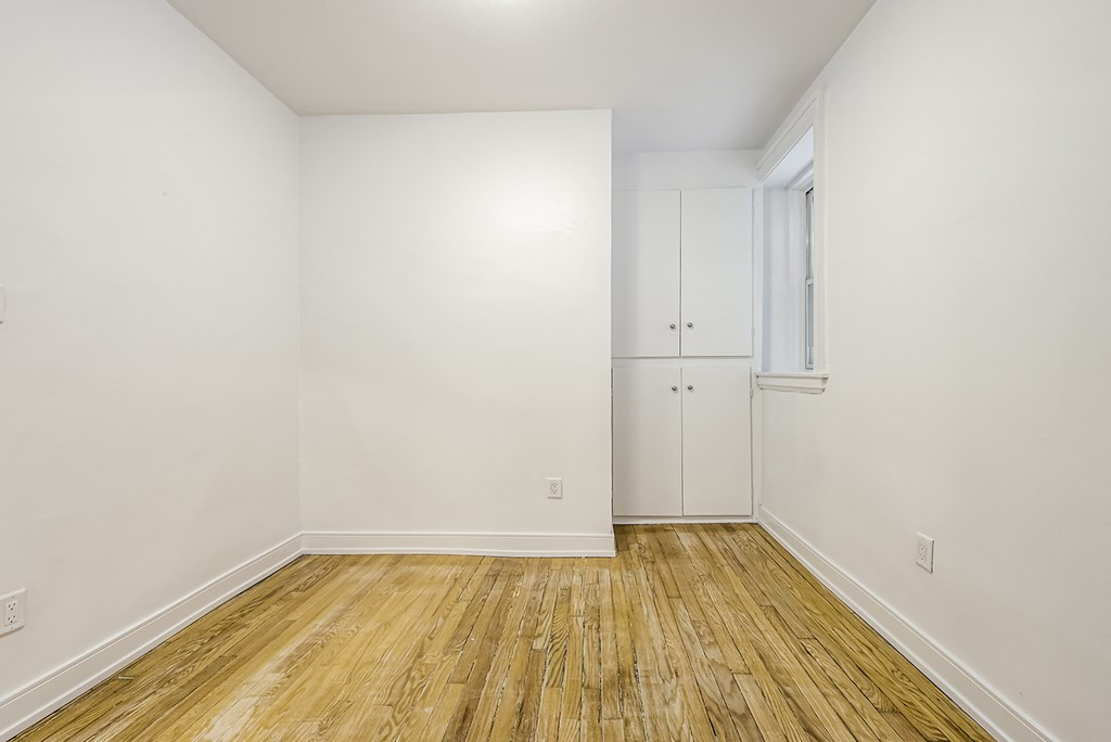 an empty room with white walls and wood floors at 723 Bloor Apartments, Toronto, M6G 1L5