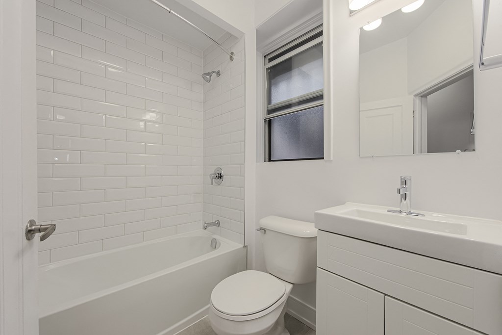 an all white bathroom with a tub and a sink and a toilet at 723 Bloor Apartments, Toronto, Canada