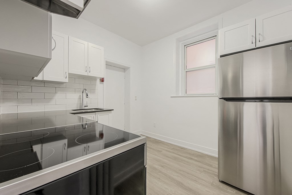A modern kitchen with a stainless steel refrigerator and a black countertop at 723 Bloor Apartments, Toronto, CA, M6G 1L5