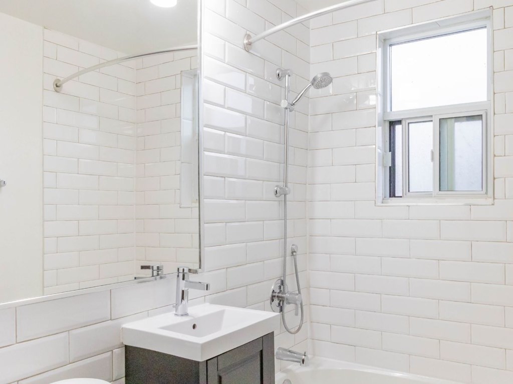 A white bathroom with a sink, mirror, and shower.