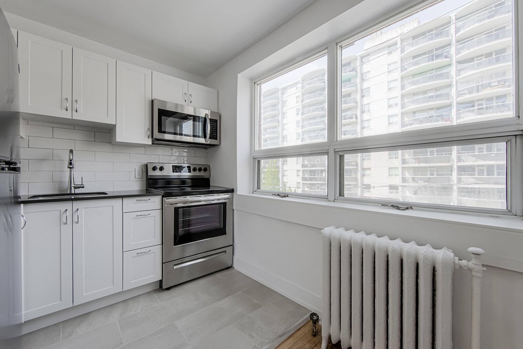 a white kitchen with a radiator and a window