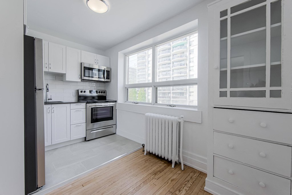a kitchen with white cabinets and a large window at 391 Sherbourne Apartments, Toronto, M4X 1K4