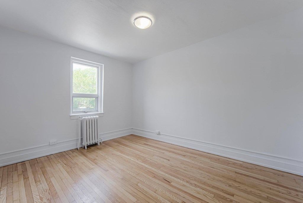 an empty room with wood floors and a window
