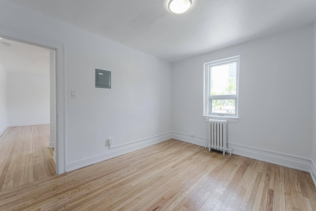 a living room with white walls and a window and wooden floors