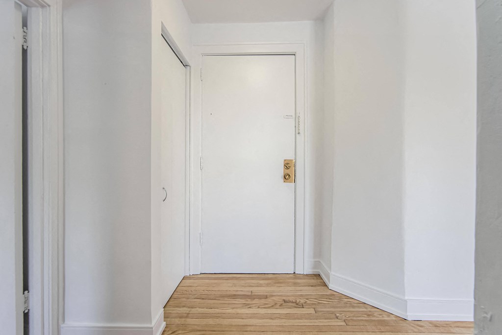 a room with white walls and a wooden floor and a white door