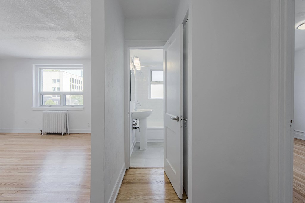 an empty room with a door open to a bathroom and a sink