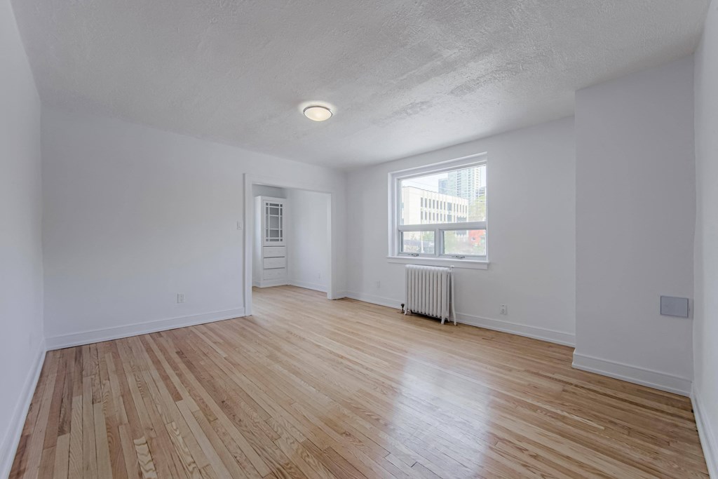 an empty living room with wood floors and a window