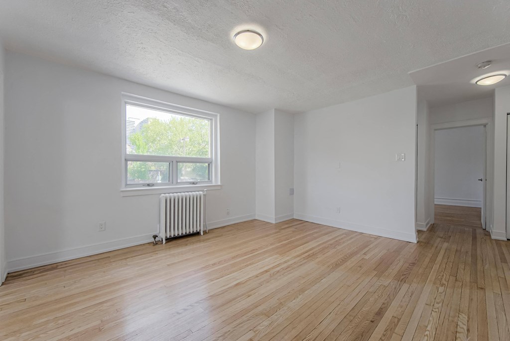 the living room of an empty house with wood floors and a window