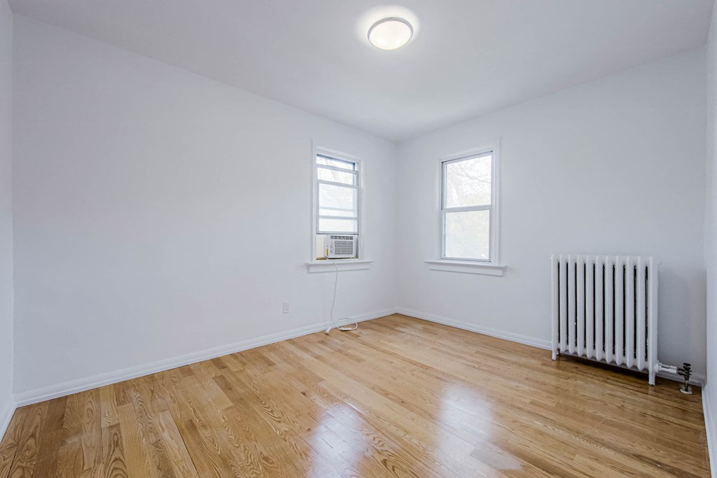 an empty room with a radiator and two windows at 83-85 Silver Birch, Toronto Canada
