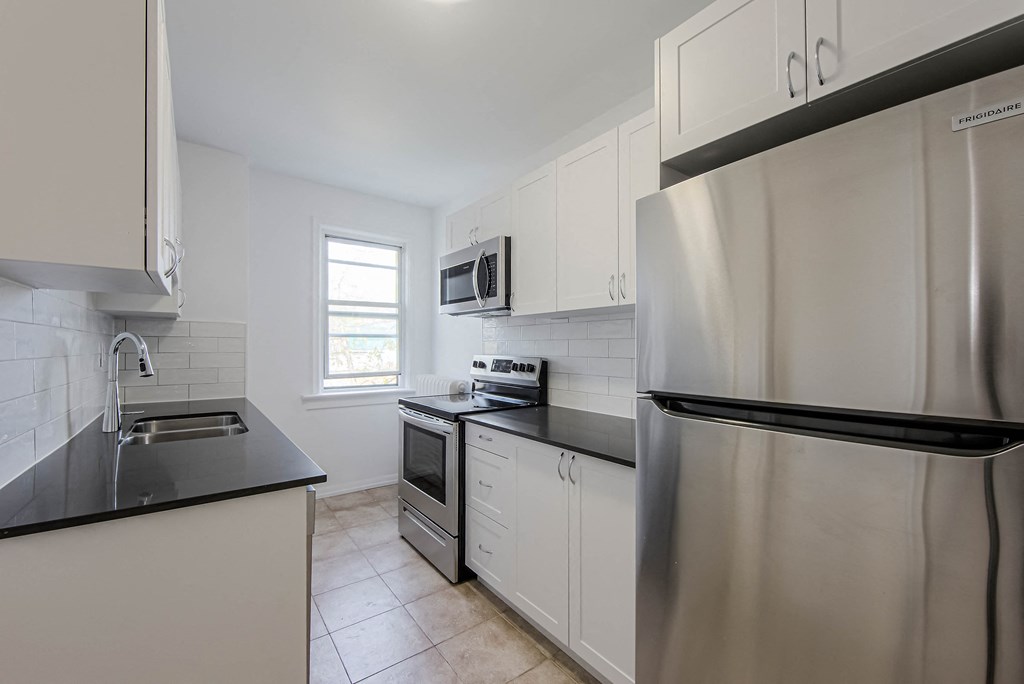 an empty kitchen with stainless steel appliances and white cabinets at 83-85 Silver Birch, Toronto, CA M4E 3L2