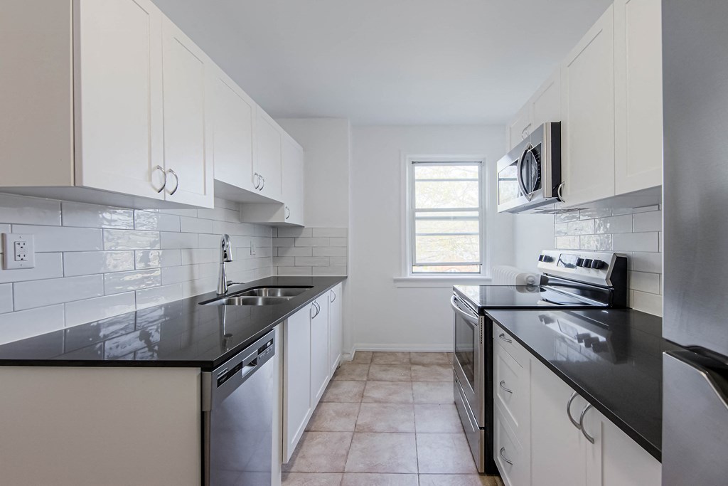 an empty kitchen with black counter tops and white cabinets at 83-85 Silver Birch, Toronto, CA M4E 3L2