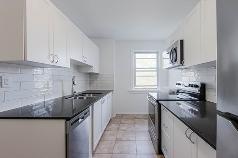 A kitchen with white cabinets and black countertops.