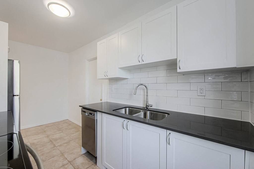 an empty kitchen with white cabinets and a sink at 83-85 Silver Birch, Toronto