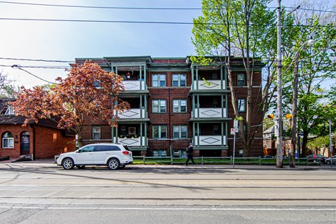 A white car is parked in front of a red brick building.