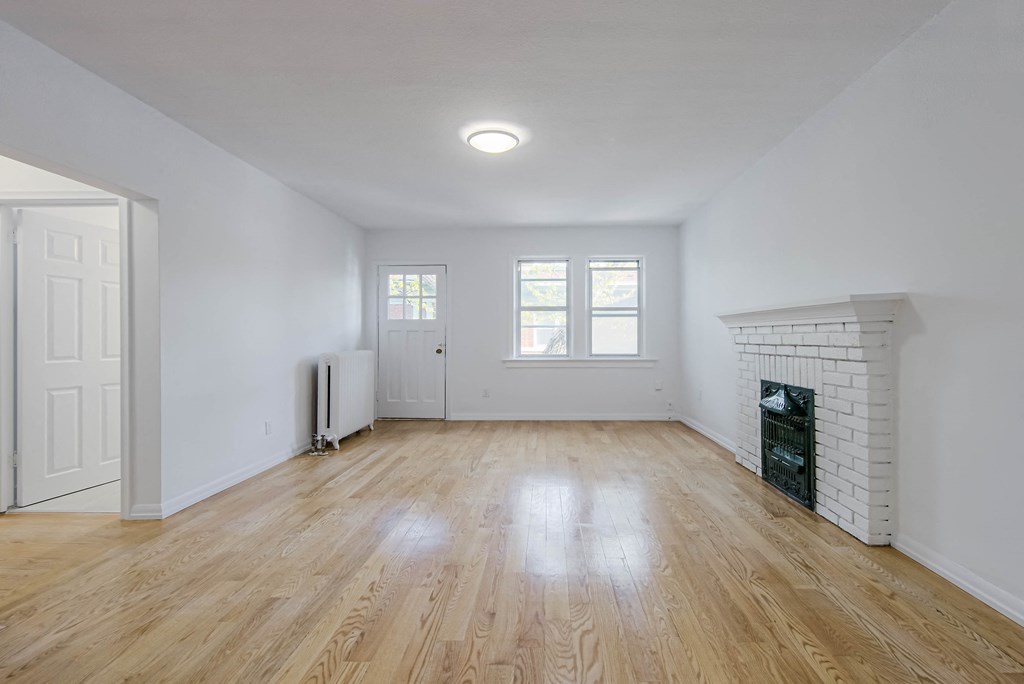 a living room with white walls and a fireplace and wooden floors at 83-85 Silver Birch, Toronto