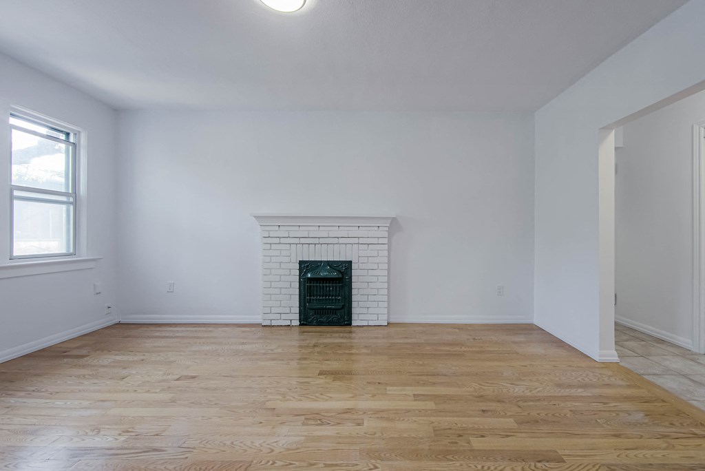 a living room with white walls and a fireplace and wooden floors at 83-85 Silver Birch, Toronto Canada