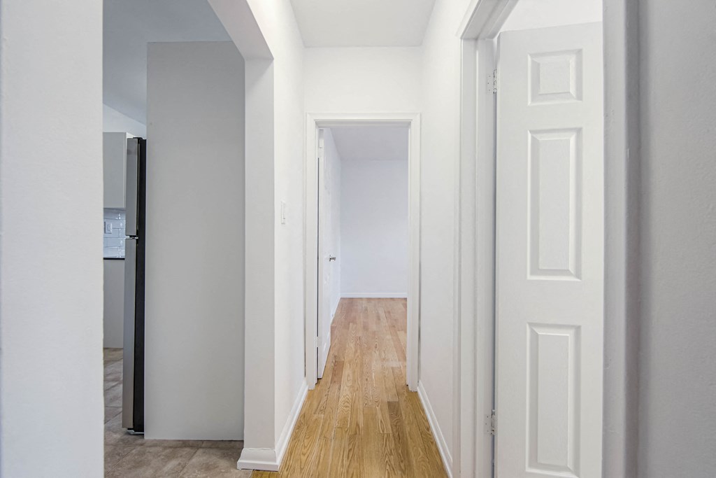 a hallway with white walls and white doors and a wood floor at 83-85 Silver Birch, Toronto, CA M4E 3L2
