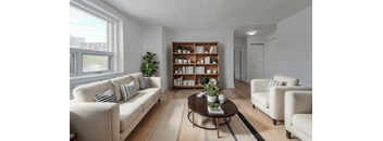 A living room with a white sofa, a wooden coffee table, and a white armchair.  at 391 Sherbourne Apartments, Toronto, Ontario