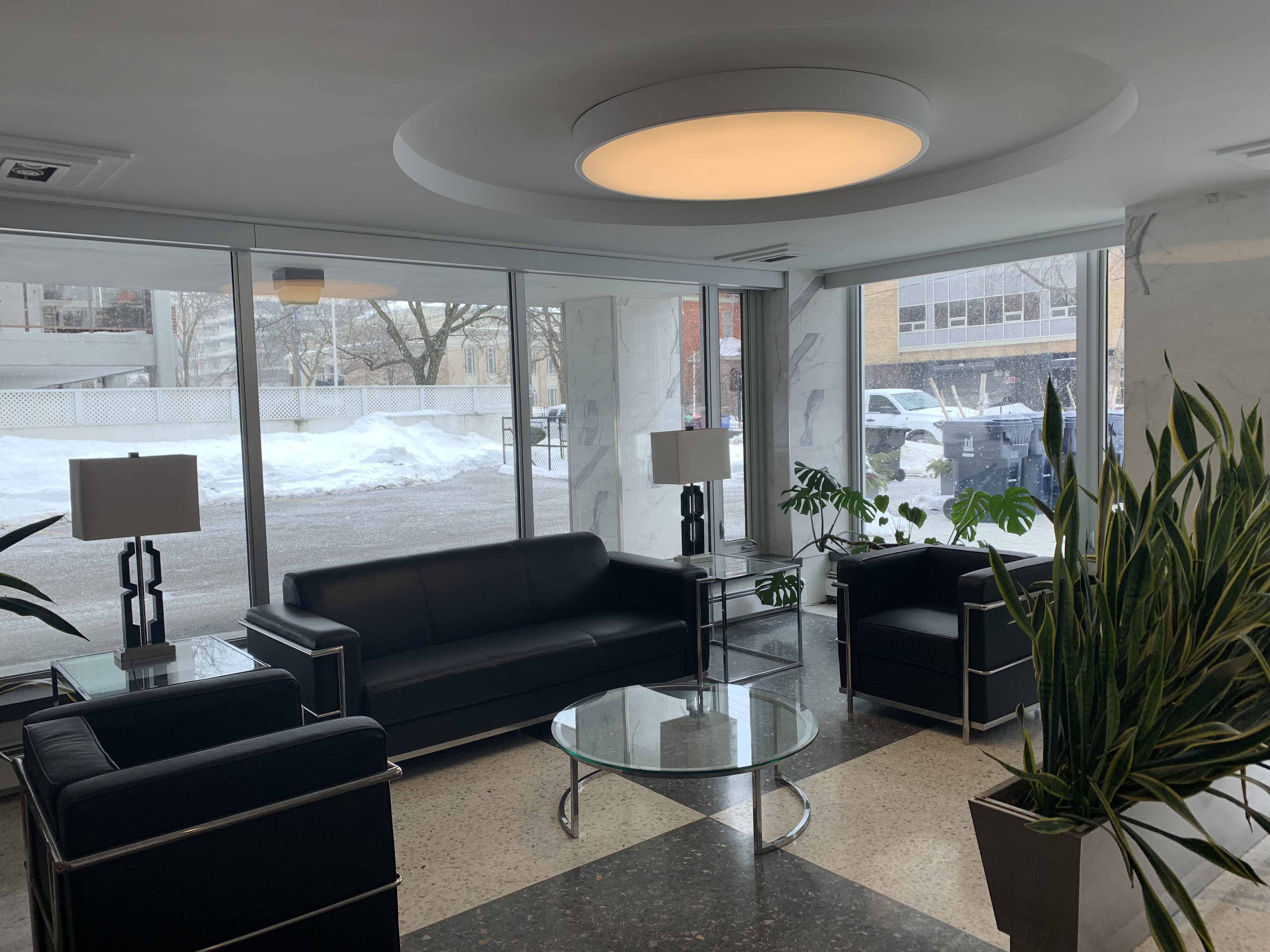 a living room with black couches and a glass table