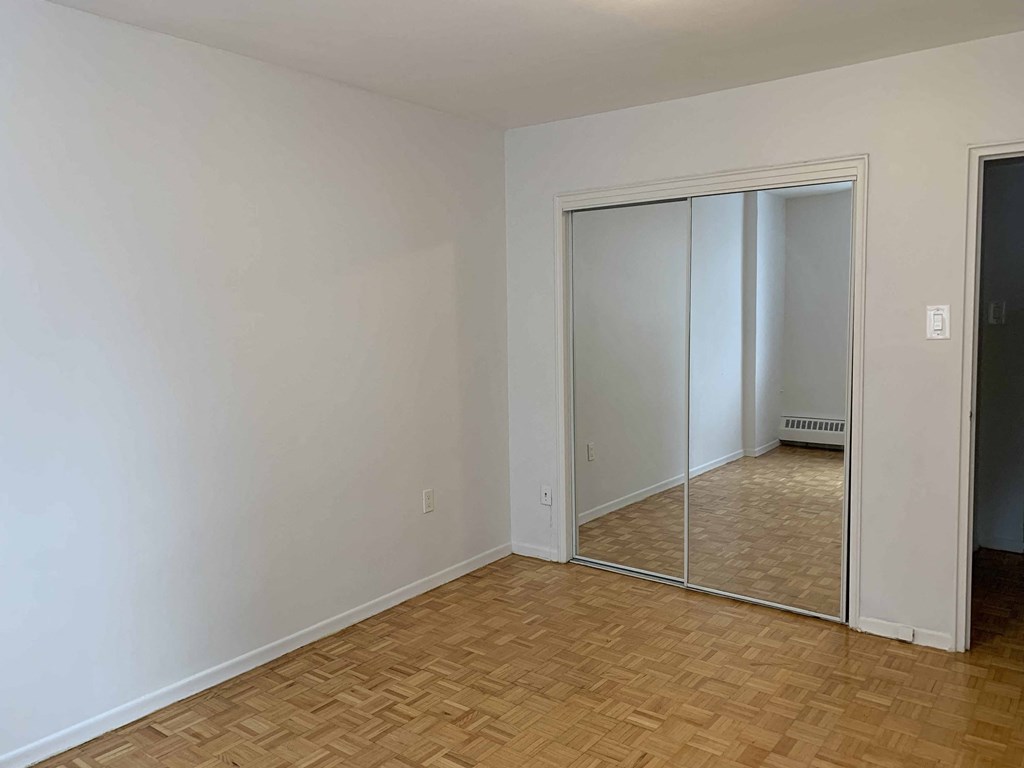 a room with a wood floor and a mirrored closet