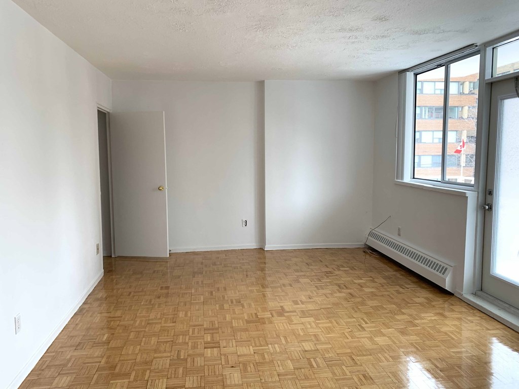 an empty living room with a wood floor and two windows