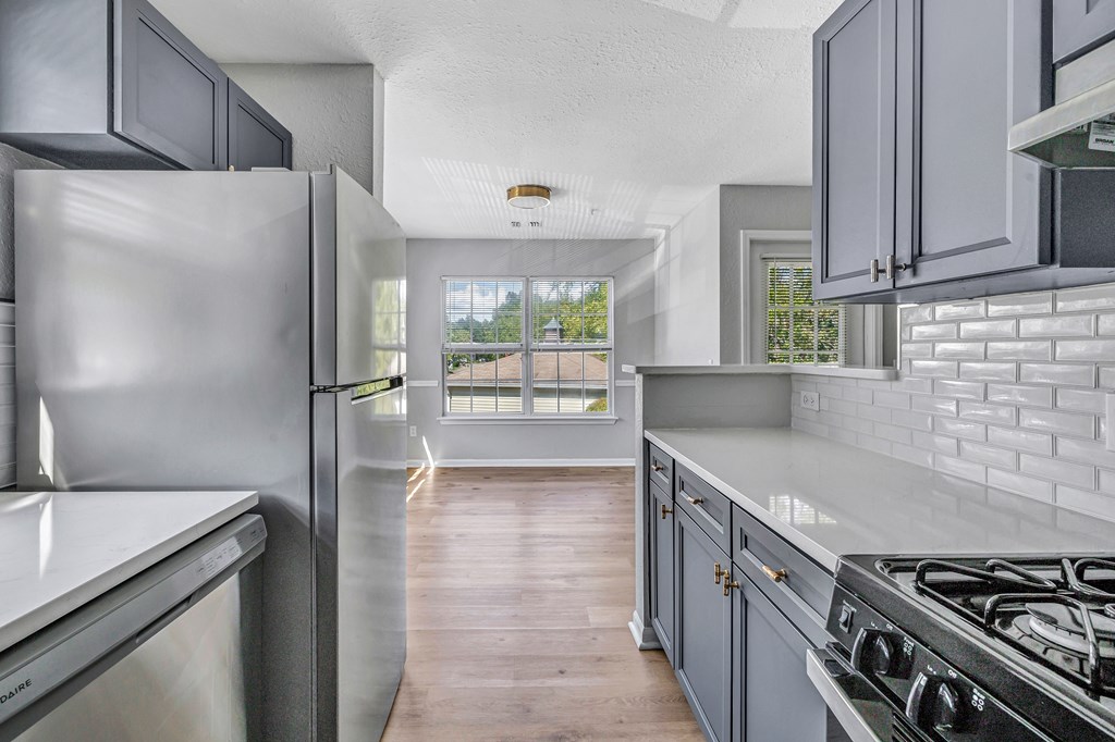 A modern kitchen with a stainless steel refrigerator and a wooden floor.