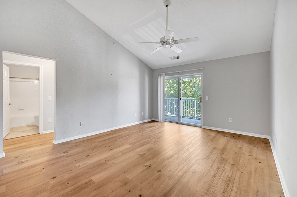 A room with a ceiling fan and sliding glass doors.