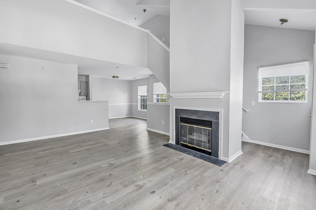 A spacious living room with a fireplace and hardwood floors.