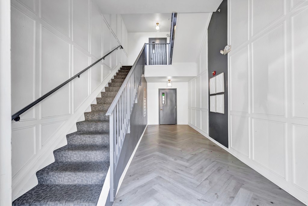 A hallway with a staircase and a door at the end.