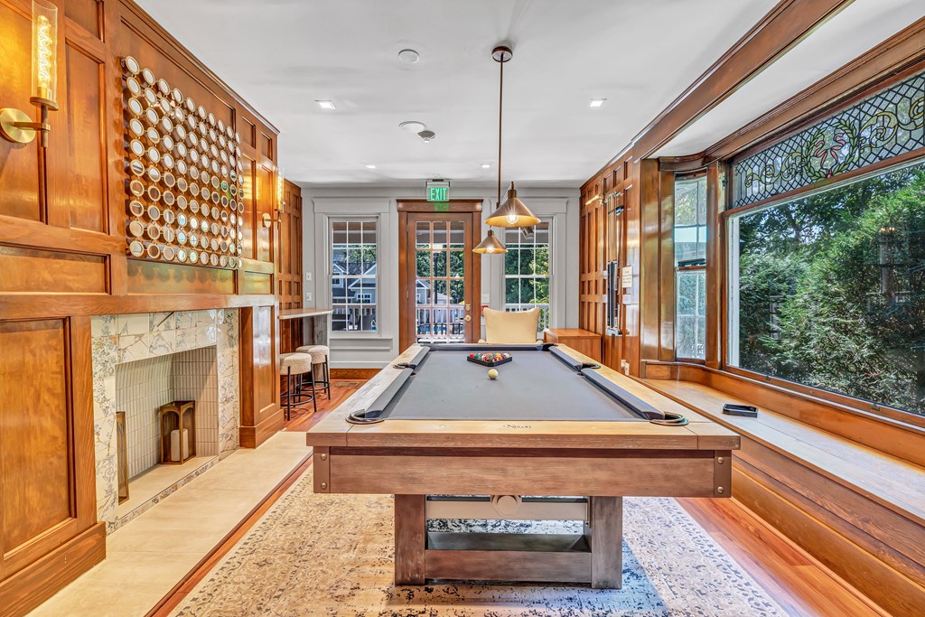 A pool table in a room with wood paneling and a fireplace.
